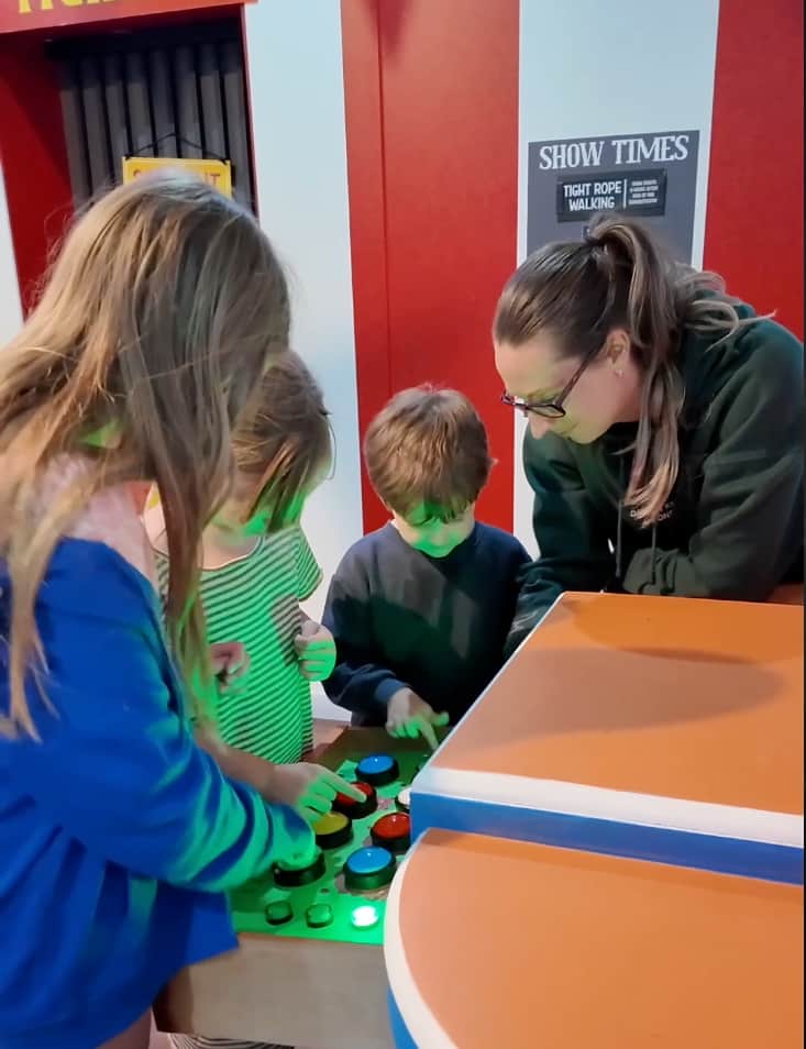 Three children and an adult working together on a colourful puzzle inside Under the Big Top.