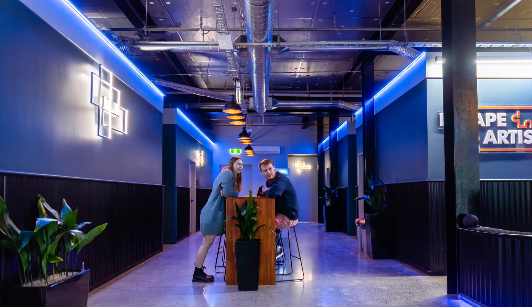 Two adult visitors talking together inside the Escape Artists Christchurch venue.