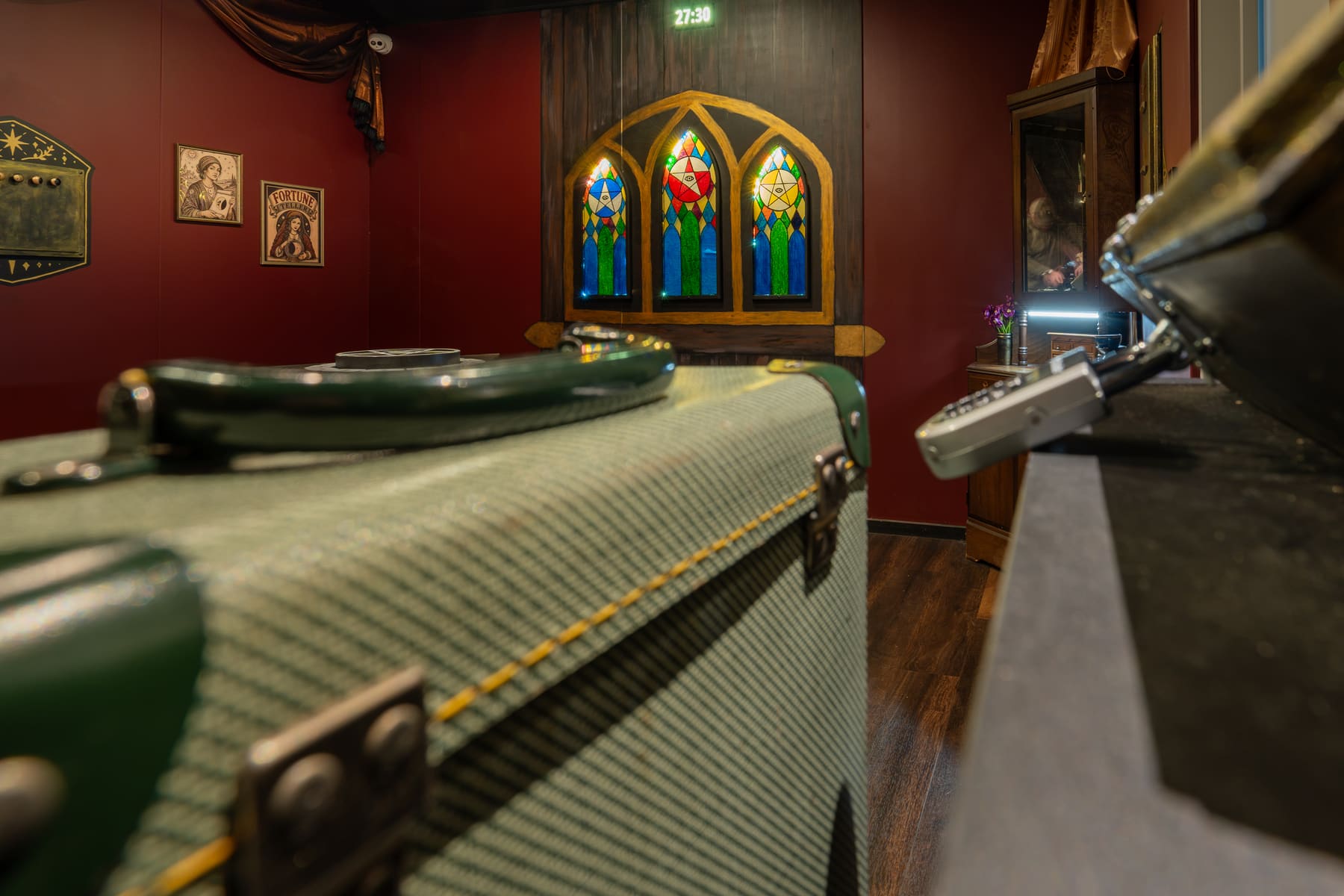 A candlelit spiritualist room with stained glass and an old suitcase inside Gracie’s Last Reading.