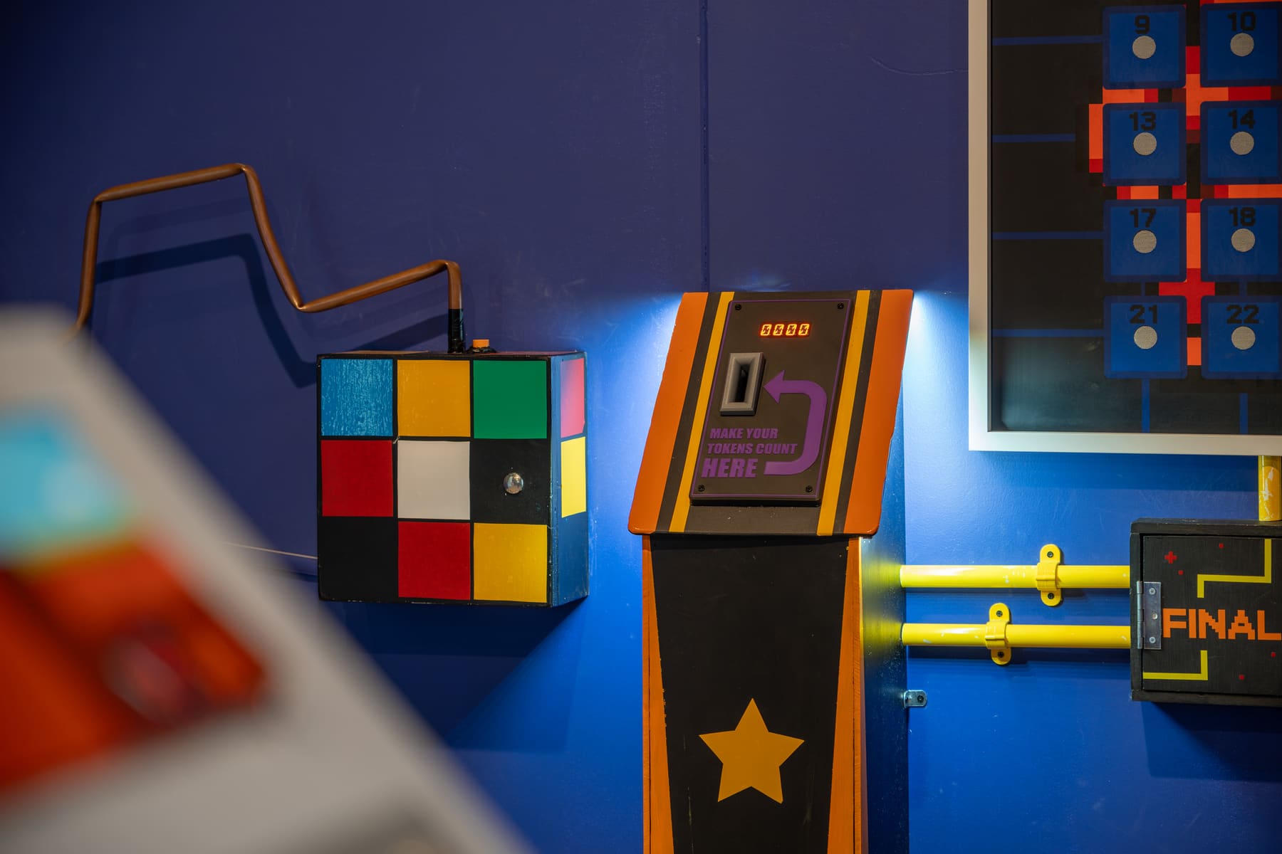 Colourful retro game controls and challenge panels inside The Arcade.