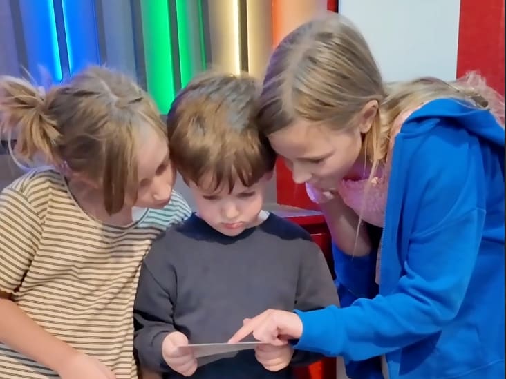 Three children working together on a clue inside Under the Big Top.
