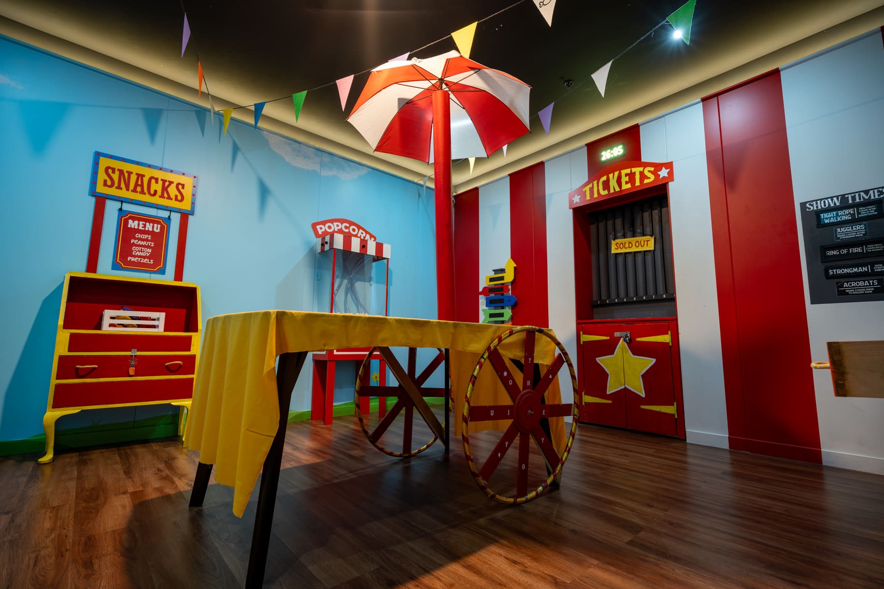 A bright circus-themed room with colourful game stations inside Under the Big Top.
