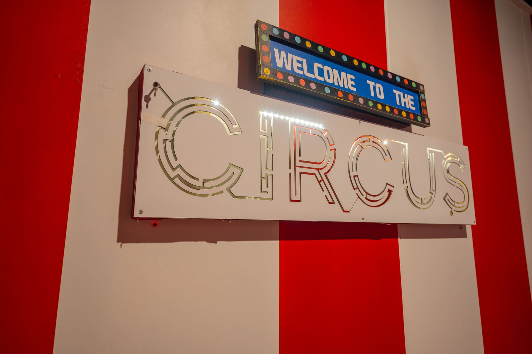 A colourful welcome sign surrounded by circus details inside Under the Big Top.